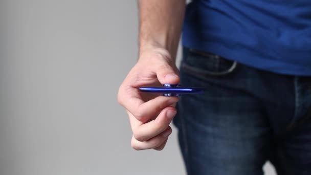 La mano de un hombre está jugando en un hilandero sobre un fondo blanco — Vídeos de Stock