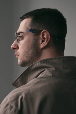 Yağmurluk ve gözlük farklı ruh halleri ile yalnız bir yakışıklı adam