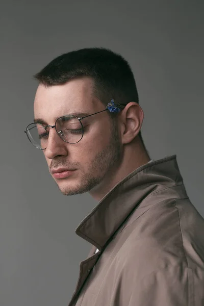 Ένα μοναχικό όμορφος άντρας με γυαλιά με διαφορετικές διαθέσεις και ένα αδιάβροχο — Φωτογραφία Αρχείου