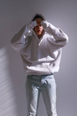 Güzel ve tatlı bir kız kot pantolon ve kazak duruyor beyaz bir duvar