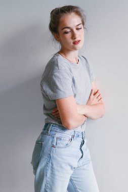 Güzel ve tatlı bir kız kot pantolon ve kazak duruyor beyaz bir duvar