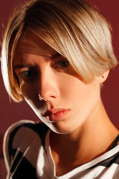 Hermosa chica con corte de pelo corto y figura deportiva sobre un fondo rojo — Foto de Stock