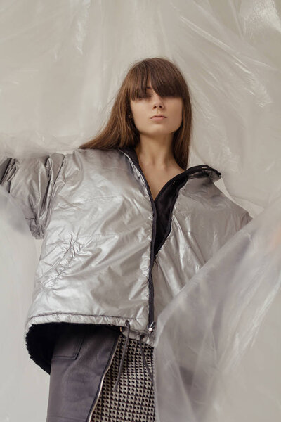 Stylish girl in fashionable clothes on the background of a translucent film