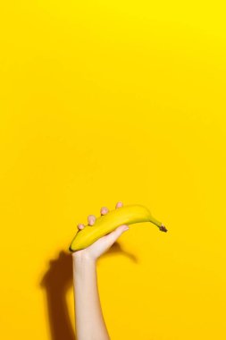 Taze muz sarı bir arka plan üzerinde el tutar