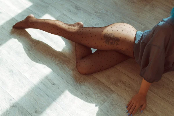 Довгі і стрункі ноги в колготках на підлозі на сонячному світлі — стокове фото