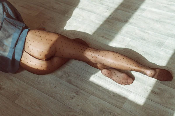 Piernas largas y delgadas en pantimedias en el suelo a la luz del sol —  Fotos de Stock