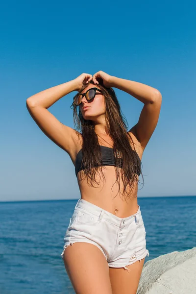 Menina na praia com cabelo molhado, bela figura e pele limpa contra o mar em tempo ensolarado — Fotografia de Stock