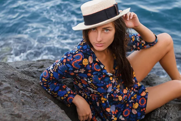 Hermosa chica en un vestido y con un sombrero en las montañas contra el mar — Foto de Stock