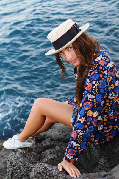 Menina bonita em um vestido e com um chapéu nas montanhas contra o mar — Fotografia de Stock