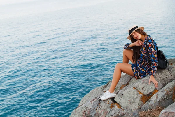 Красивая девушка в платье и в шляпе в горах у моря — стоковое фото