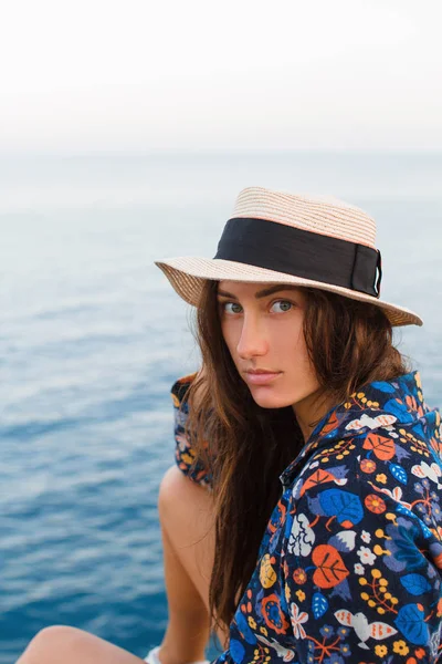 Hermosa chica en un vestido y con un sombrero en las montañas contra el mar — Foto de Stock