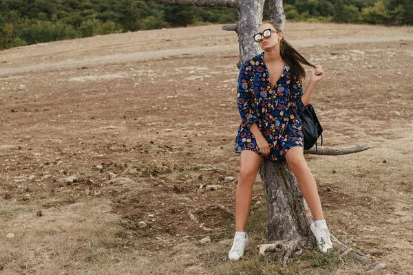 Hermosa chica viajera en un vestido y con gafas camina en los espacios abiertos — Foto de Stock