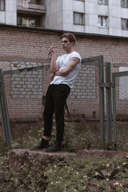 Yakışıklı ve şık bir adam eski terkedilmiş sokaklarda yürüyor