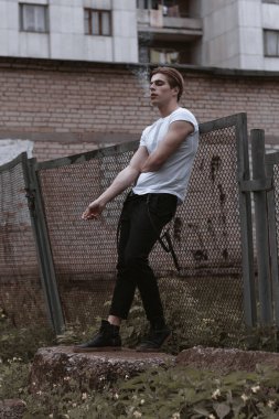 Yakışıklı ve şık bir adam eski terkedilmiş sokaklarda yürüyor