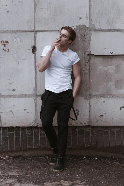 A handsome and stylish guy walks the old abandoned streets