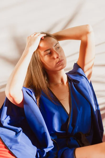 Beautiful girl in blue silk robe resting in the sunlight