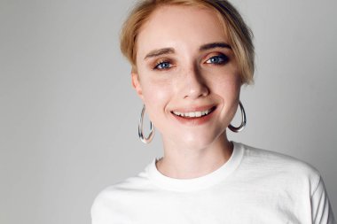 Beyaz bir arka planda beyaz bir T-shirt üzerinde kısa bir saç modeli ile güzel bir kızın portreleri