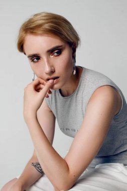 Beyaz bir arka planda beyaz bir T-shirt üzerinde kısa bir saç modeli ile güzel bir kızın portreleri