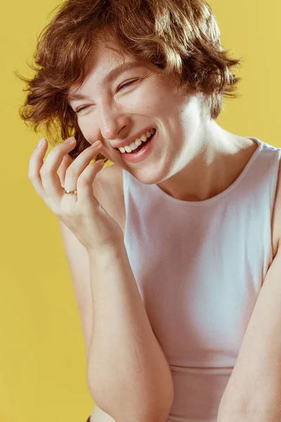 Güzel ve duygusal bir kız makyaj olmadan ve doğal cilt ile sarı bir arka plan üzerinde