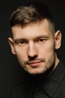 Siyah bir arka plan üzerinde siyah gömlekli adam yakışıklı ve olumlu