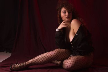 Kumaş arka plan üzerinde stüdyoda kıvırcık saçlı güzel kızıl saçlı kız