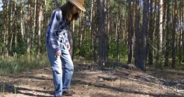 Genç adam yere oturur ve toprakta çam ormanı inceliyor