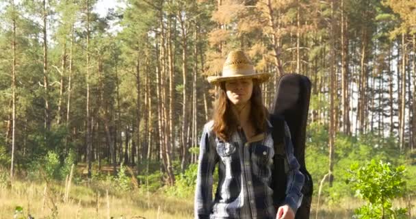 Jonge man met klassieke gitaar wandelingen in bos — Stockvideo