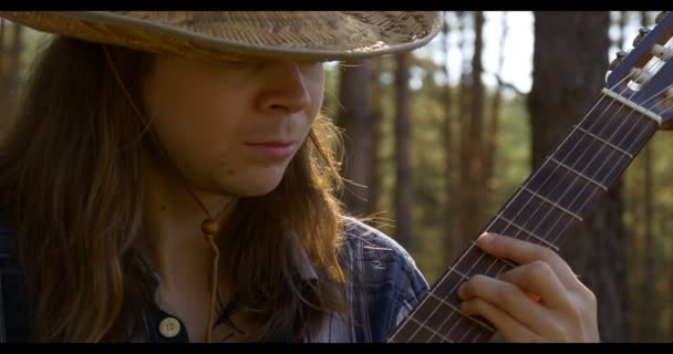 Joven toca la guitarra clásica en el bosque de pinos — Vídeo de stock