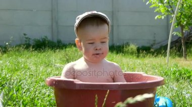 Gülümseyen ve su bir kase içinde oynayan sevimli küçük çocuk