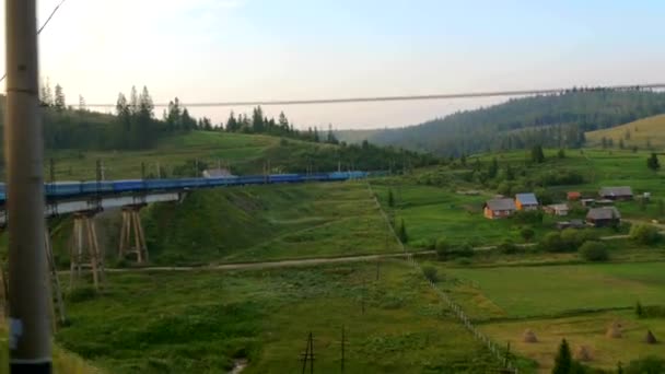 Uitzicht uit het raam van bewegende trein - brug, vallei, bergen, dorp — Stockvideo