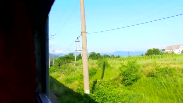 Vista da janela do trem em movimento - Aldeia, campo. Culturas. montanhas — Vídeo de Stock