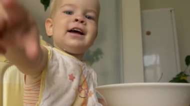 Mutlu küçük çocuk gülüyor, gülüyor ve parmak işaret. Anne oğlu şapkasını koyar