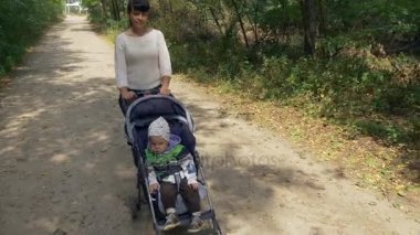 Anne bebek arabası orman yoluyla de kırsal yol itiyor. Yakın çekim