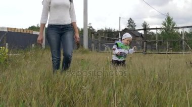 Çim, yürür küçük çocuk düşüyor. Kalkıp anne yardımcı olur