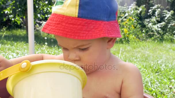 Bonito menino tomando banho e brincando na água com balde de brinquedo — Vídeo de Stock