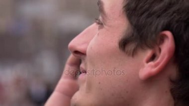 Mutlu genç adam görüşmeler bir cep telefonu. Yakın çekim. Şehir arka plan, insanlar, arabalar. Europe