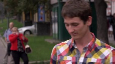 Adam akıllı telefonda konuşurken yürür. Şehir, insanlar, arabalar