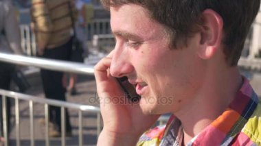 Genç adam görüşmeler bir cep telefonuyla görünüyor Maidan Nezalezhnosti Meydanı, trafik, insanlar, arabalar