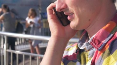 Genç bir cep telefonu üzerinde görüşmeler adam. Yakın çekim. Şehir Meydanı, trafik, insanlar, arabalar