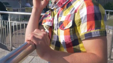 Genç bir cep telefonu üzerinde görüşmeler adam. Yakın çekim. Şehir Meydanı, trafik, insanlar, arabalar