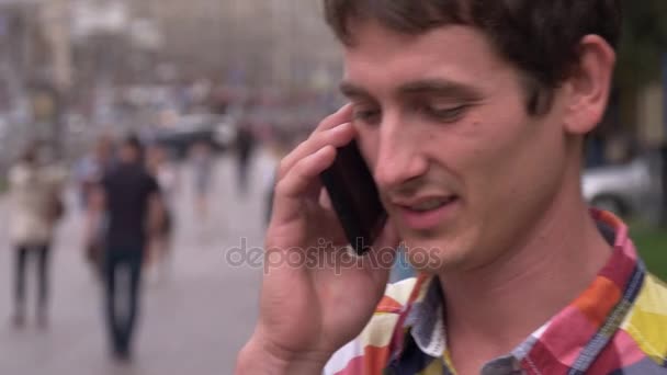 Der junge Mann folgt einem Anruf und beginnt zu gehen und zu sprechen. Stadt, Menschen, Autos — Stockvideo