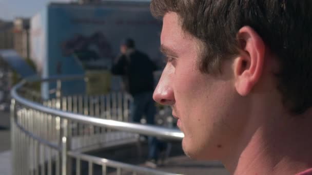 El hombre está mirando la ajetreada vida de la ciudad en la calle, en la plaza. Kiev, Ucrania, tráfico, personas, coches — Vídeo de stock