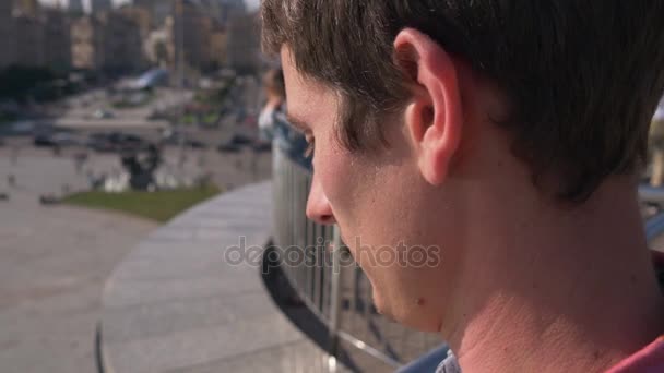 L'homme regarde la place de la ville, les gens, les voitures en mouvement — Video