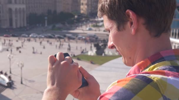 Vida ocupada da cidade, trânsito. Homem usando telefone inteligente no fundo da cidade — Vídeo de Stock