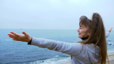 Deniz kenarında uçurumun kenarında üzerinde gülümseyen mutlu olgun kadın