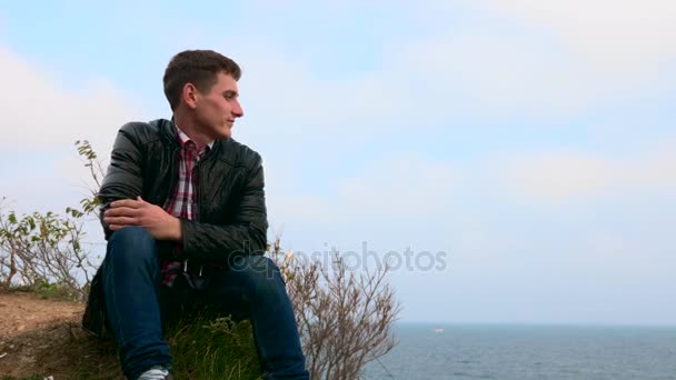 Młody Człowiek Siedzi Skraju Urwiska Patrząc Morze — Wideo stockowe