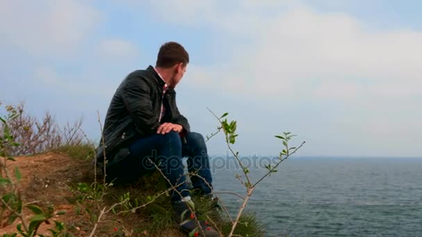 Молодой Человек Сидит Краю Скалы Смотрит Море — стоковое видео