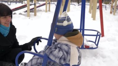 Mutlu anne çalış çocuğunu üstünde kar ile kaplı Bahçesi. Ağır çekim. Blizzard sonra kış City