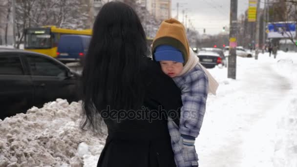 美しい母親は 街でかわいい子と歩きます 冬の雪の日 スローモーション — ストック動画
