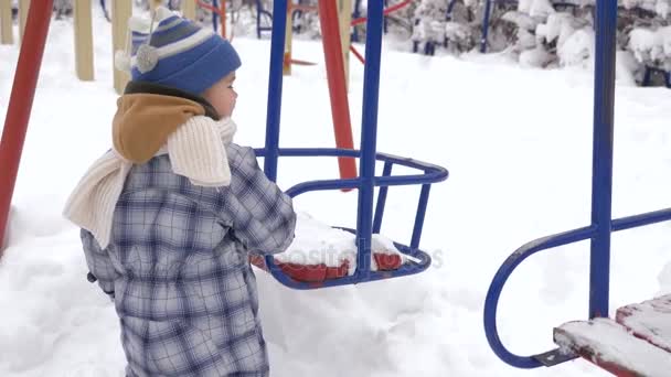 Maluch Wygląda Huśtawki Pokryte Śniegiem Slow Motion Zimowe Miasto Blizzard — Wideo stockowe